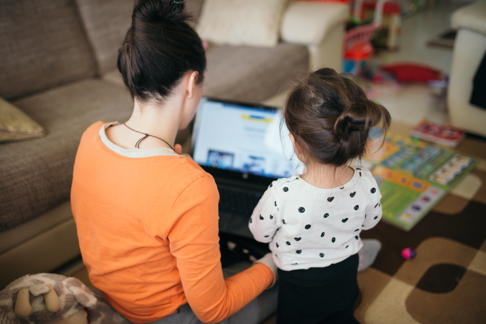 mom teaches daughter for work on laptop