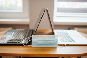 Surgical mask between two laptops on the kitchen table