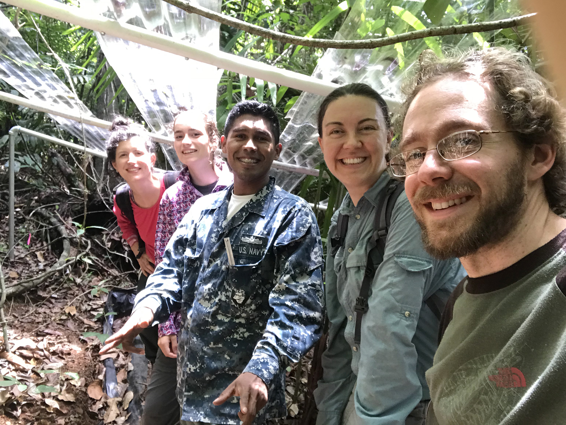 Five people stand under infrastructure in a rainforest
