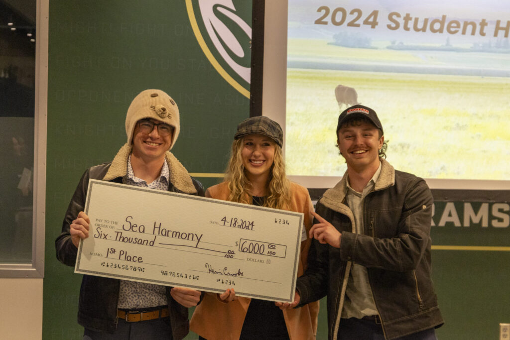 Three Colorado State University students hold a giant check for $6,000 in prize winnings for the Handprint Challenge